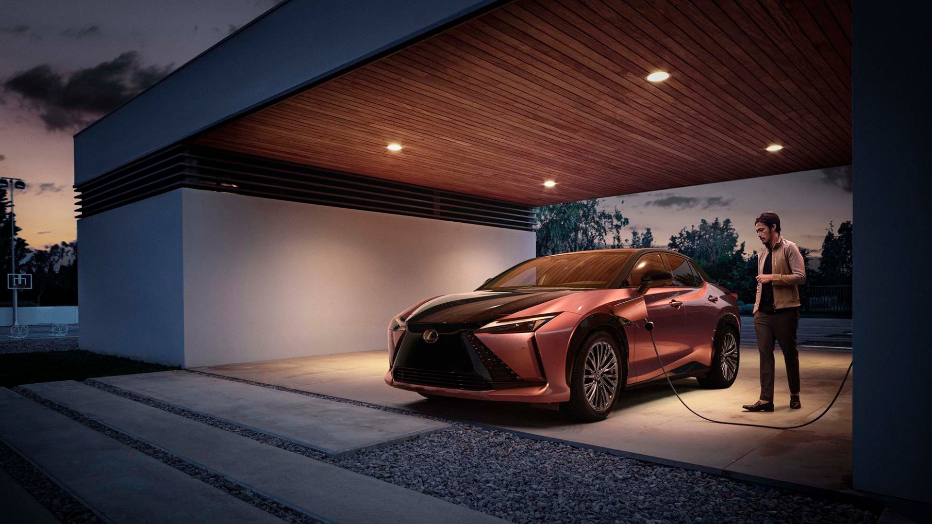 Man stands next to a charging RZ, at nighttime.